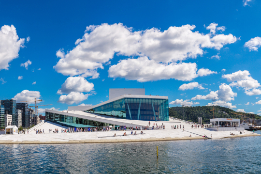 Blick vom Wasser aus auf ein futuristisches Gebäude in hellgrau in Oslo