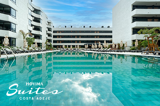 Hotelpool im Vordergrund, rechts und links Hotelgebäude in weiß